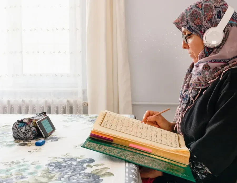 quran reading with tajweed online female teacher Woman in hijab studying the Quran from a Mushaf during an online Tafseer class